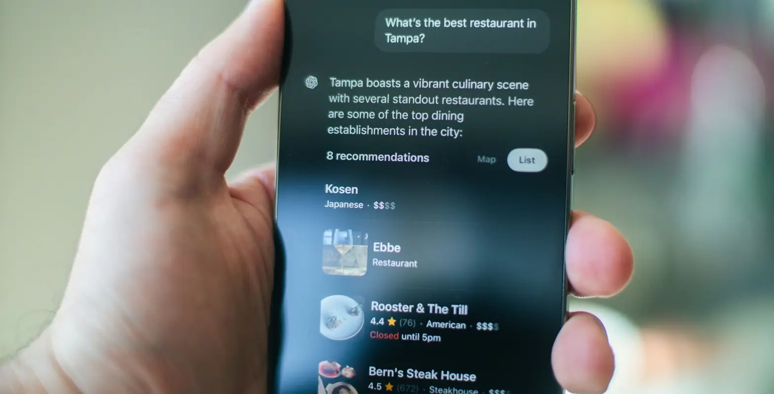 Hand hält ein Smartphone, auf dem ChatGPT Restaurant-Empfehlungen mit Sternebewertungen zeigt